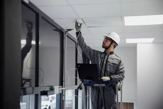 Un homme en train d'installer un outil de sécurité sur le plafond 